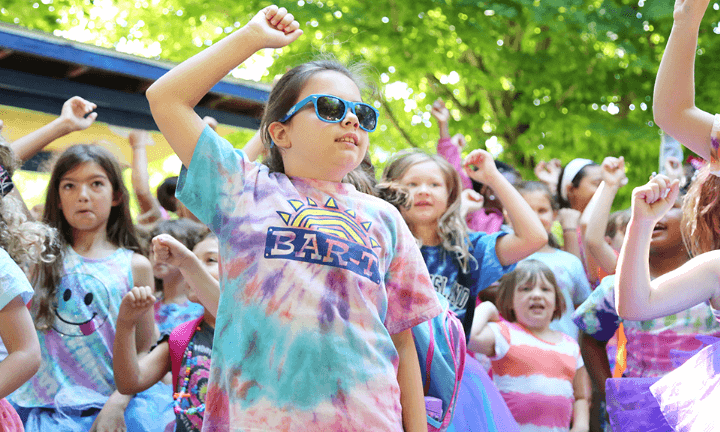 Young campers dancing and jumping with sunglasses on