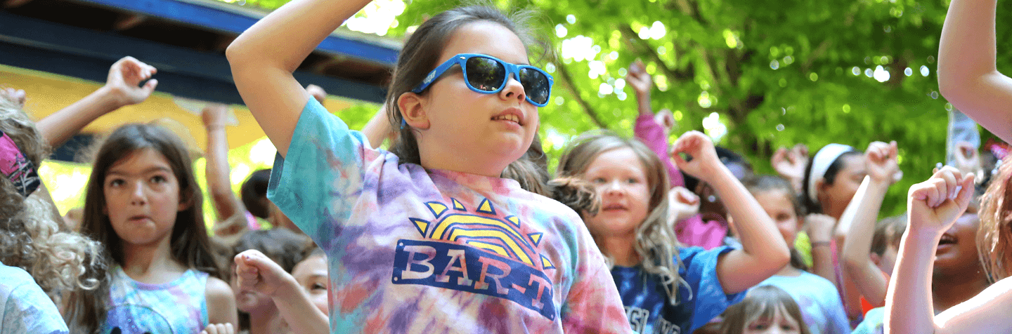 Young campers dancing and jumping with sunglasses on