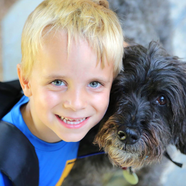 Young boy camper smiling next to a dog
