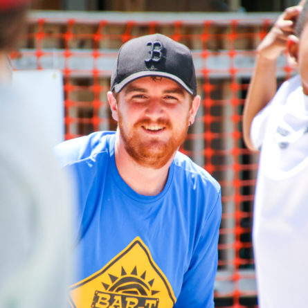 Male staff member smiling and watching kids play a game