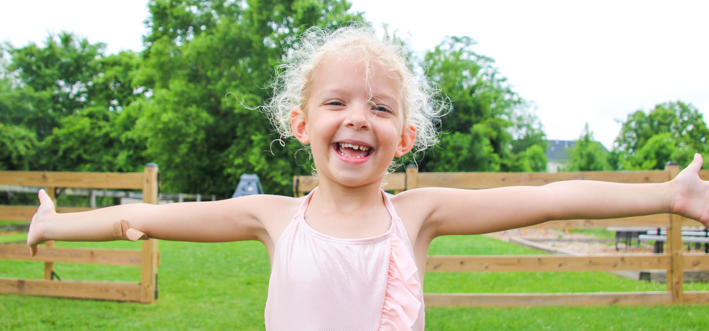 Young girl camper in a smiling with arms wide open for the camera