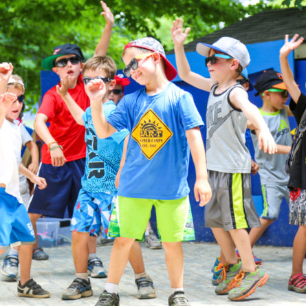 Group of boy campers dancing in sunglasses on the stage