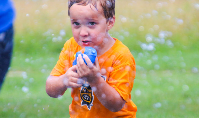 Young boy camper with a bubble gun toy shooting bubbles