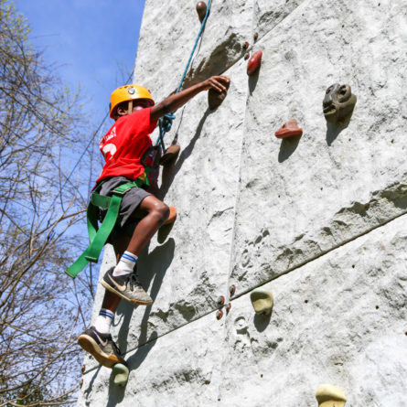 Camper climbing up the outside rock wall