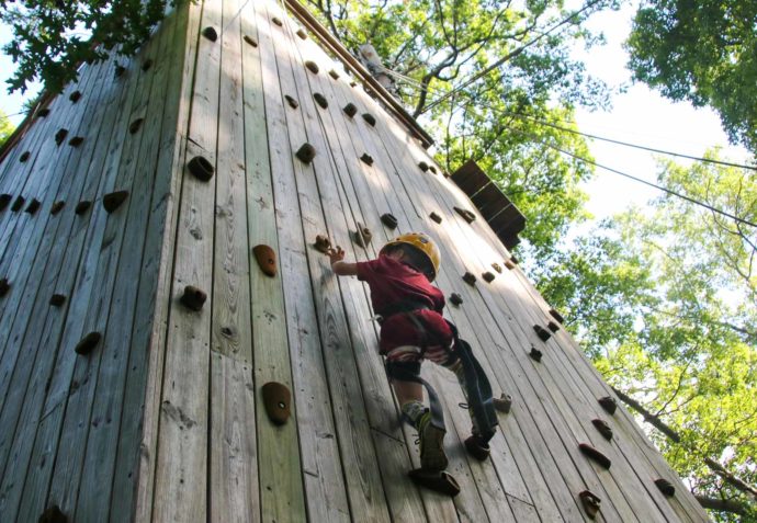 Camper climbing an advanced climbing wall outside