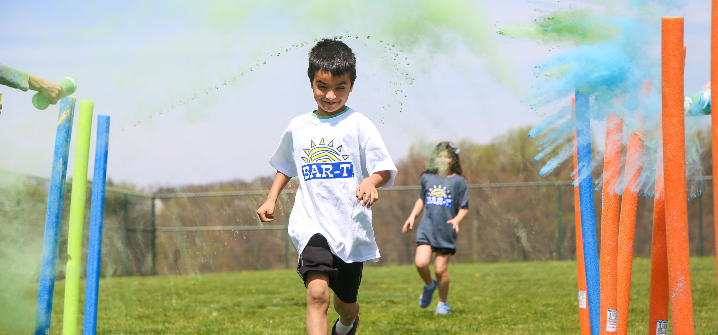 Camper running in a color run with color chalk being thrown at him