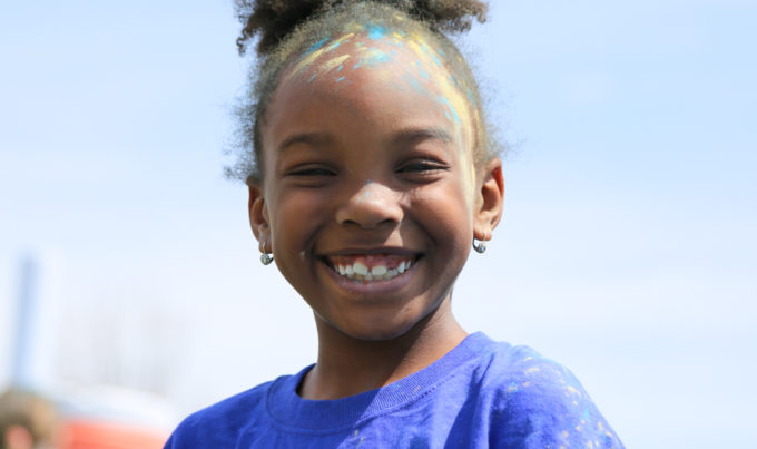 Girl camper after the color run smiling with colored chalk on her