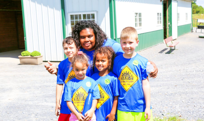 Counselor taking a group photo with four campers all in blue shirts