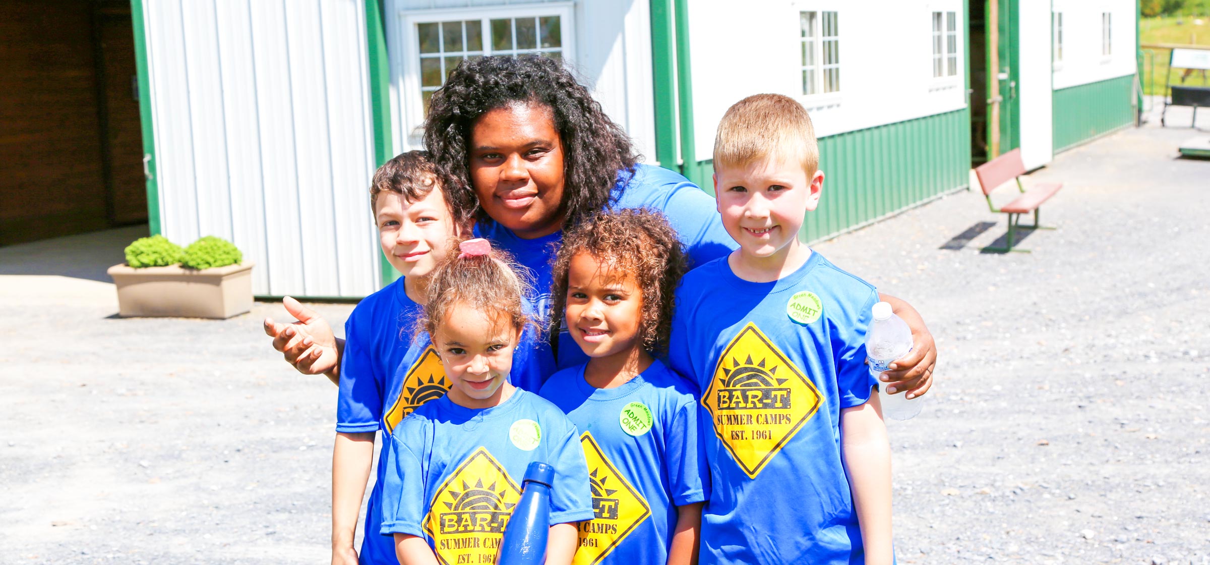 Counselor taking a group photo with four campers all in blue shirts