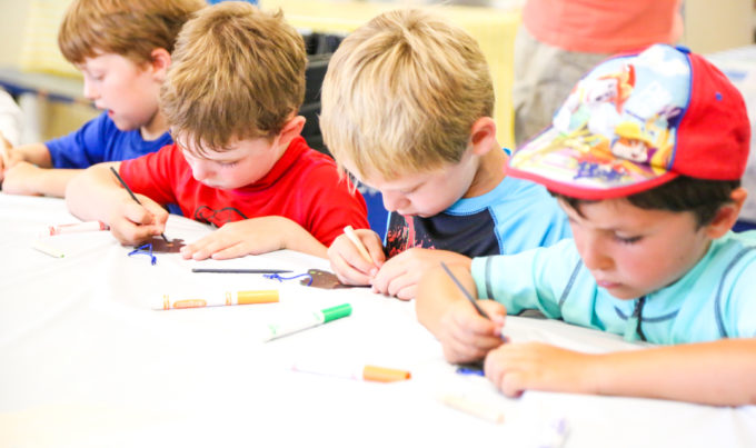 Campers sitting at a table coloring with markers