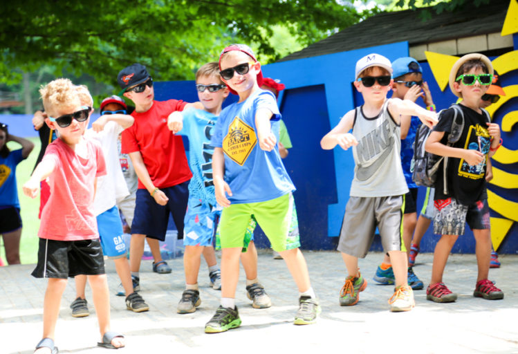 Campers on stage outside dancing with sunglasses on