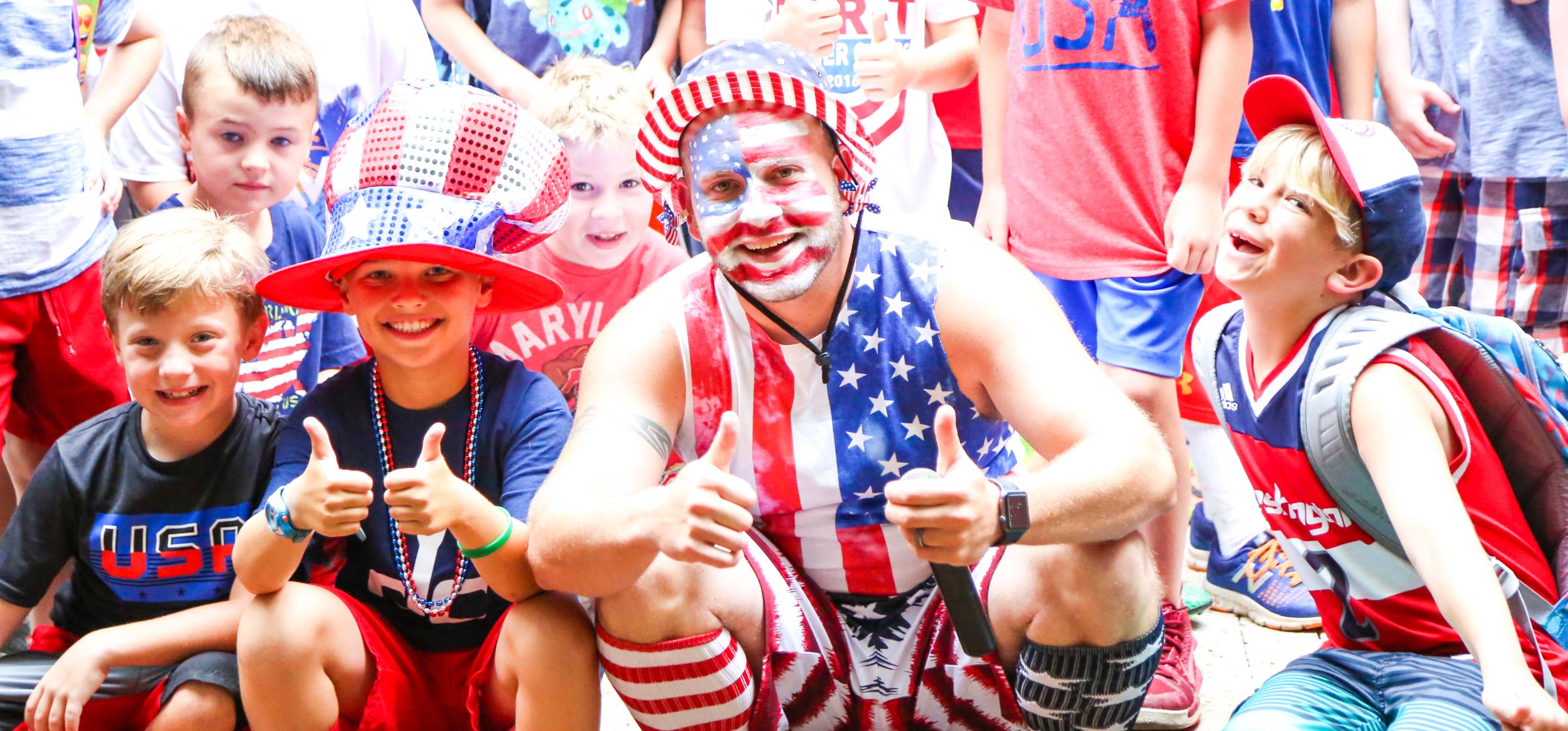 Counselor sitting amongst campers all with fourth of July face paint and outfits on