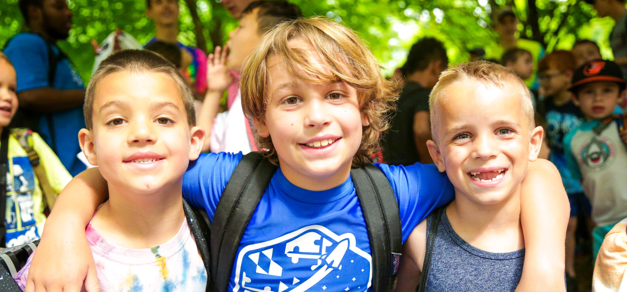 Three friends with arms around each other smiling for the photo