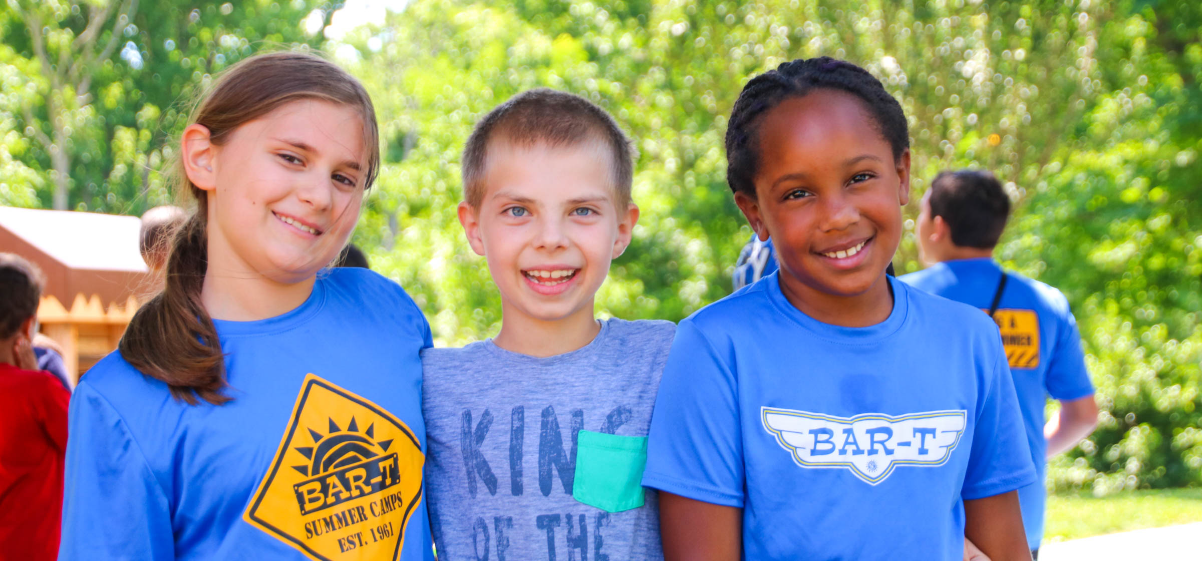 Three friends standing and smiling together for a photo outside