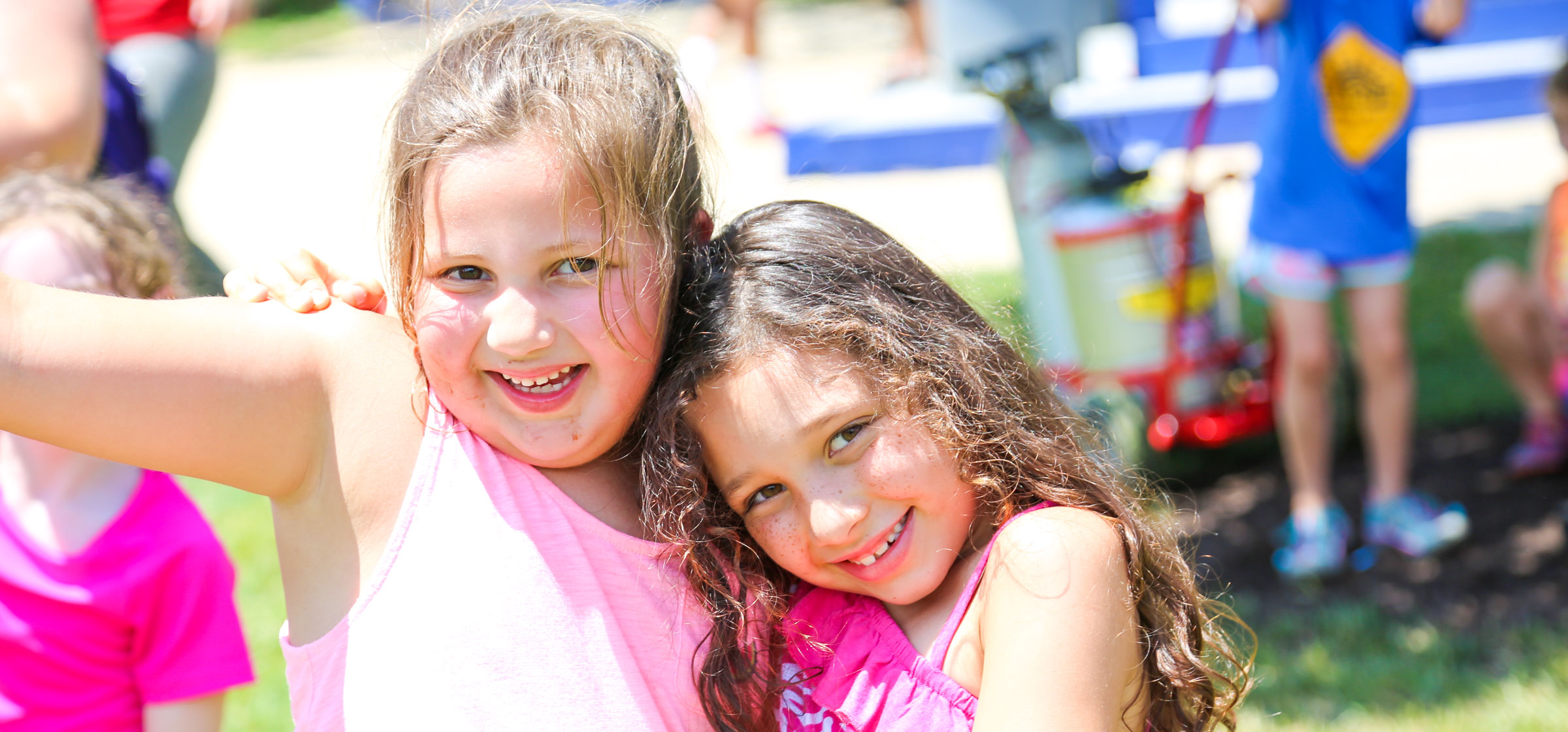 Two friends in pink smiling with arms around each other for a photo