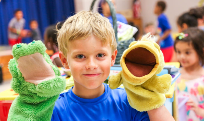 Camper with a hand puppet on each hand smiling for the camera