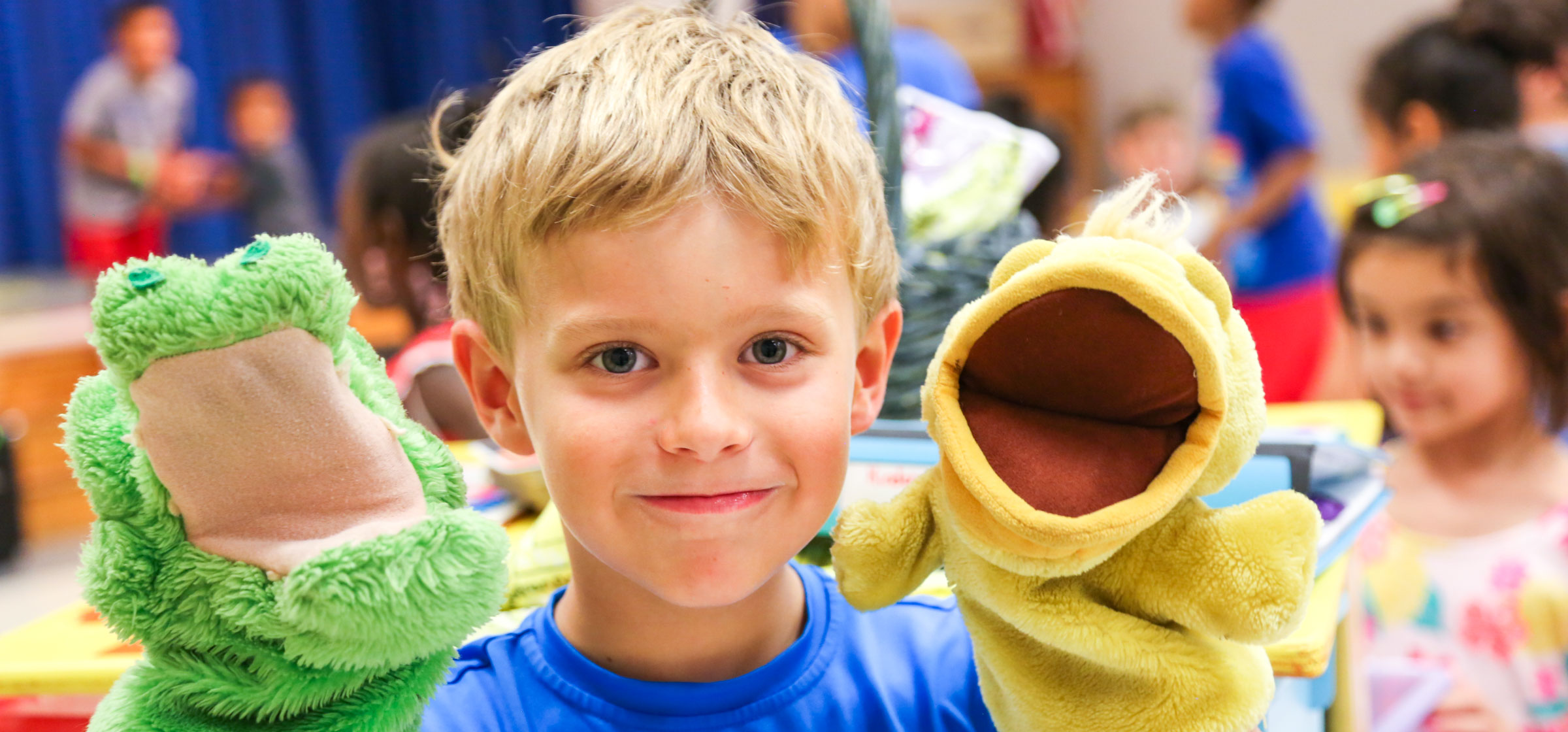 Camper with a hand puppet on each hand smiling for the camera