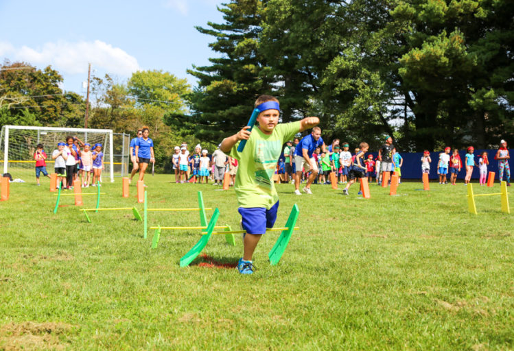 Boy camper running through a relay race with a baton