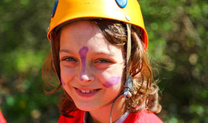 Camper with a rock climbing helmet on a face paint