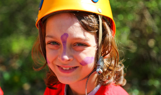 Camper with a rock climbing helmet on a face paint