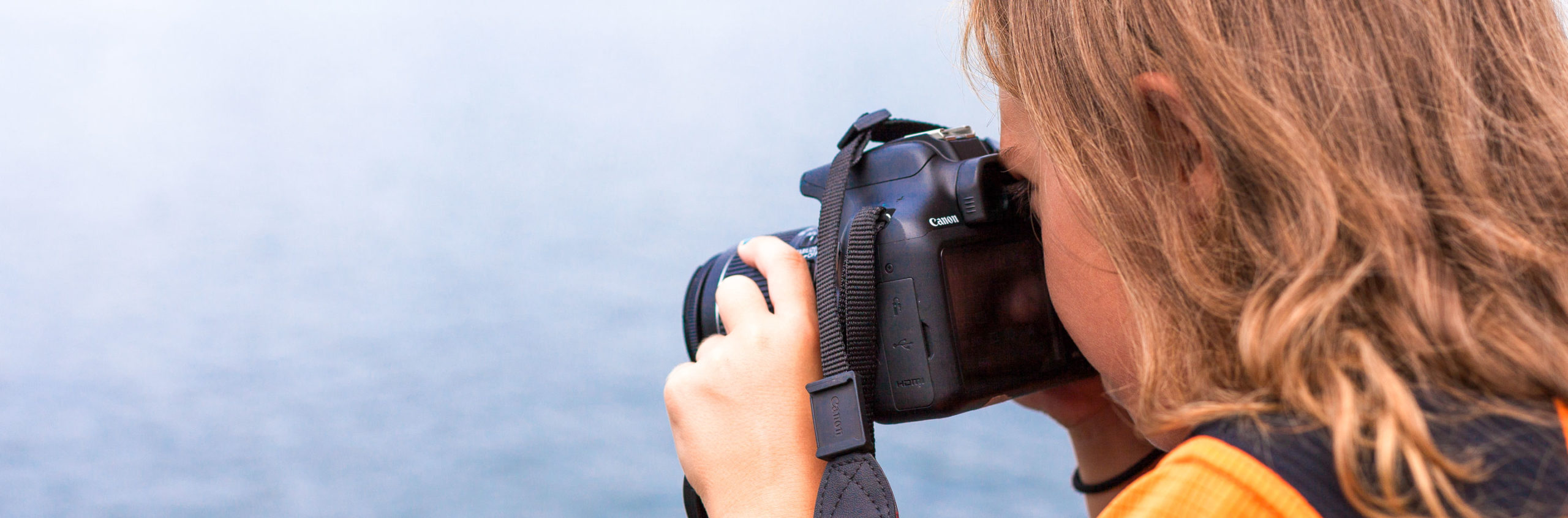 Girl taking a photo of water with a DSLR camera