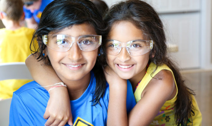 Two girls with science goggles on smiling for the camera