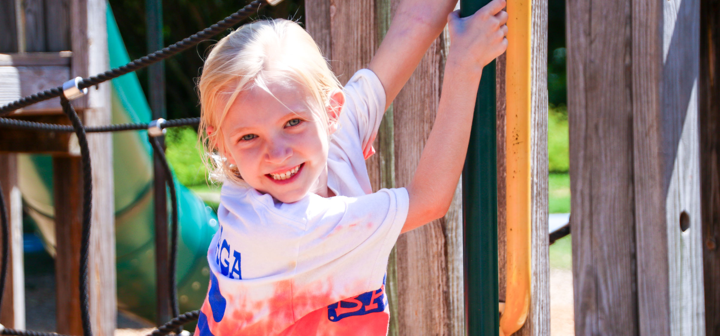 Girl camper on the jungle gym smiling