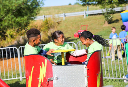 Three campers in a carnival spinning ride having fun