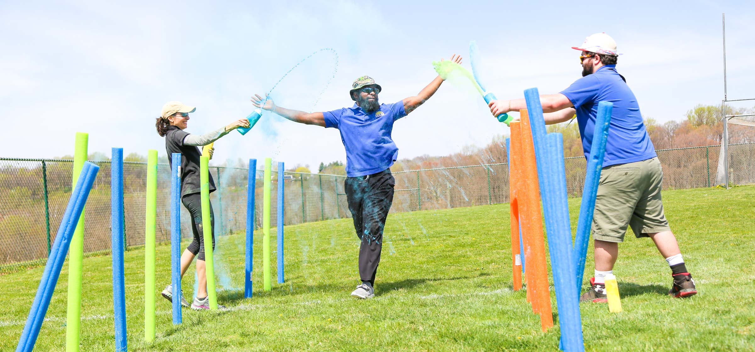 Counselor running through the color run course getting sprayed with color by other counselors