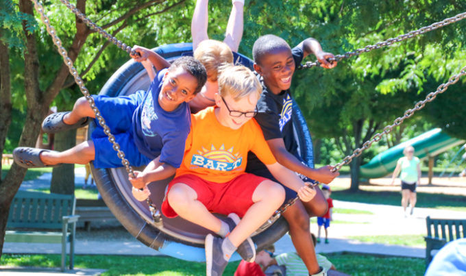 Four friends on a tire swing having fun