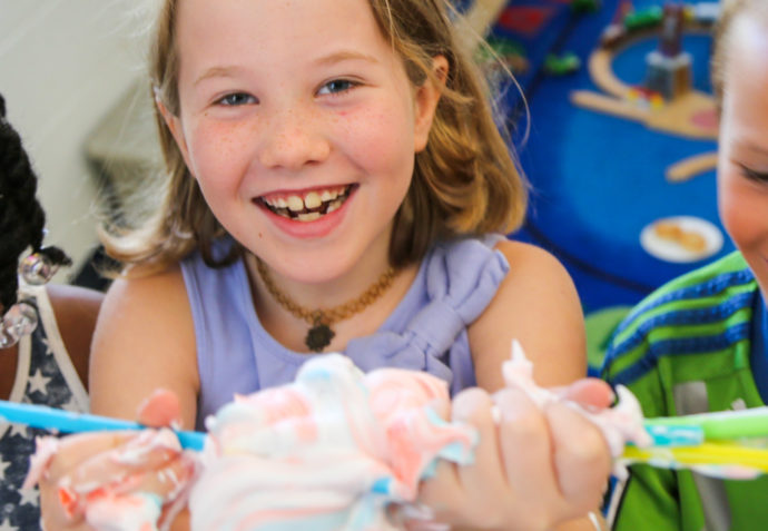 Three campers holding up a clump of toothpaste with straws sticking out of it