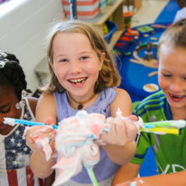 Three campers holding up a clump of toothpaste with straws sticking out of it