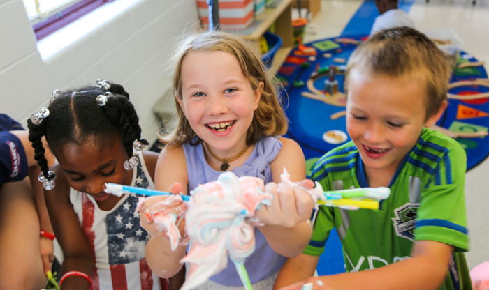 Three campers holding up a clump of toothpaste with straws sticking out of it