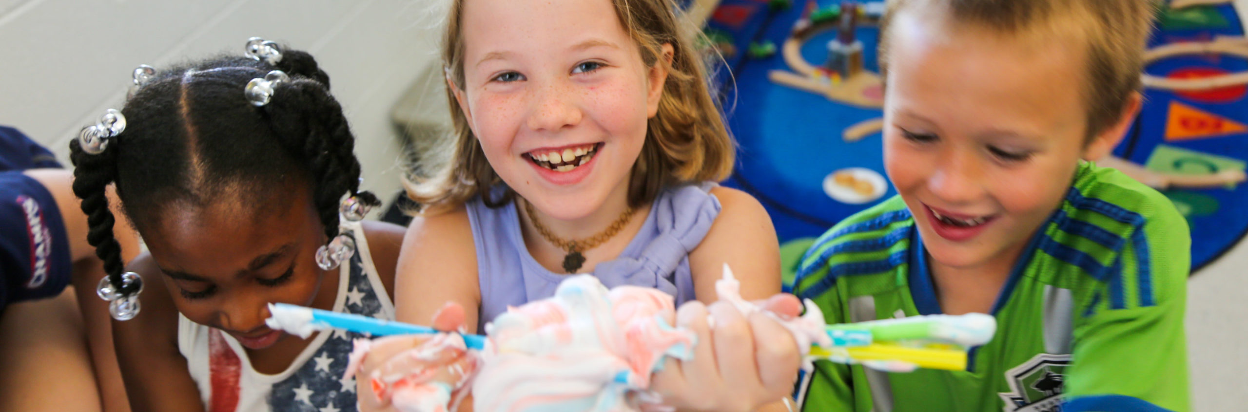 Three campers holding up a clump of toothpaste with straws sticking out of it