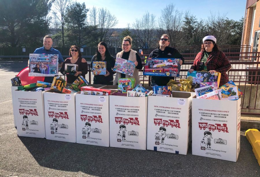 One adult standing behind each bin of toys lined up outside for the toys for tots drive