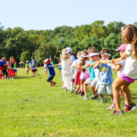 Groups of campers playing tug-o-war on a field