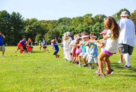 Groups of campers playing tug-o-war on a field