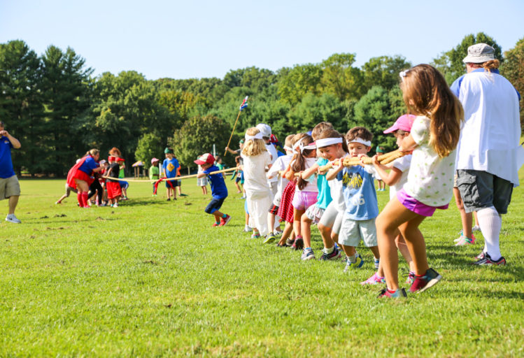 Groups of campers playing tug-o-war on a field