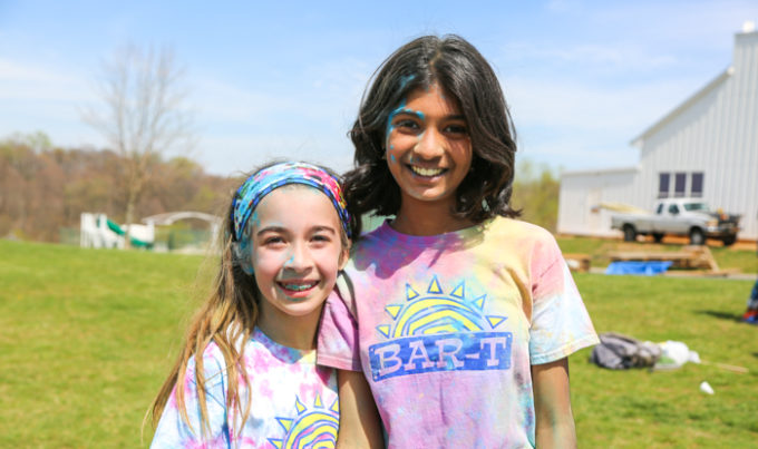 Two campers smiling for the photo after a color run covered in colored chalk