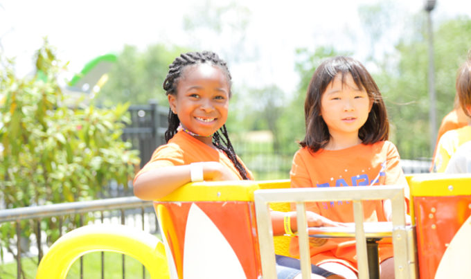 Two campers on a fun fair ride smiling at the camera