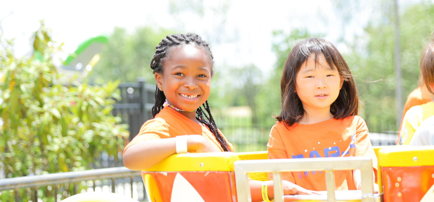 Two campers on a fun fair ride smiling at the camera