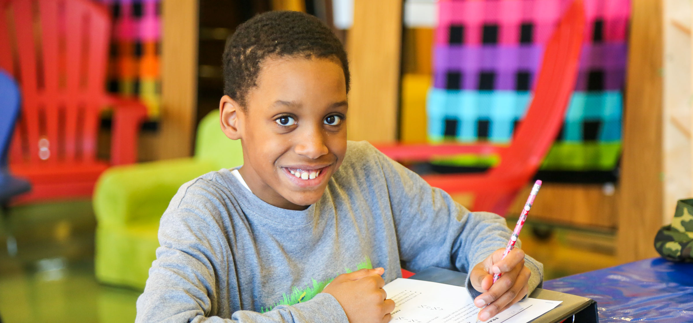 Child working on homework sitting at a table smiling