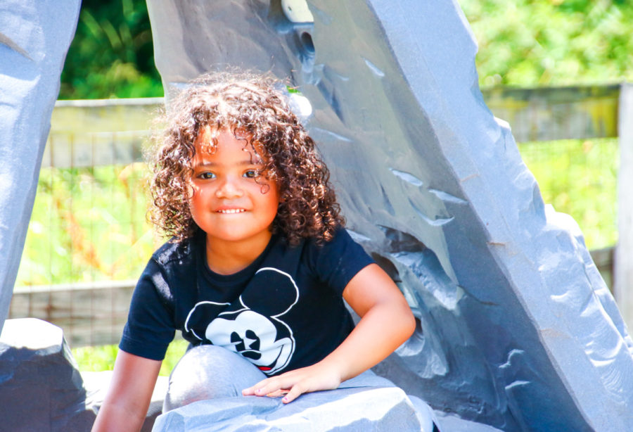 Young boy camper climbing through a playground structure